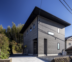 グレーの外壁と深い庇が特徴的な二階建ての新築注文住宅の外観